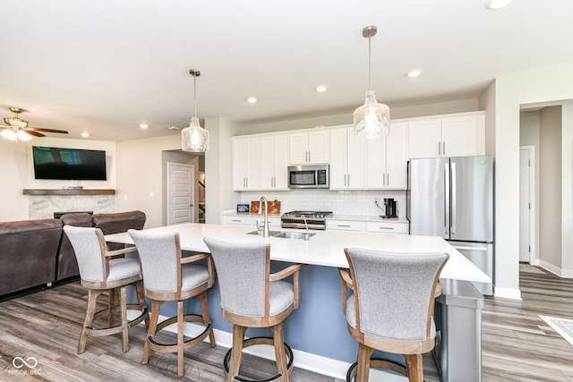 16502 Dominion Dr, Fishers, IN 46040 - kitchen with stainless steel appliances, light countertops, wood finished floors, a kitchen island with sink, and white cabinets