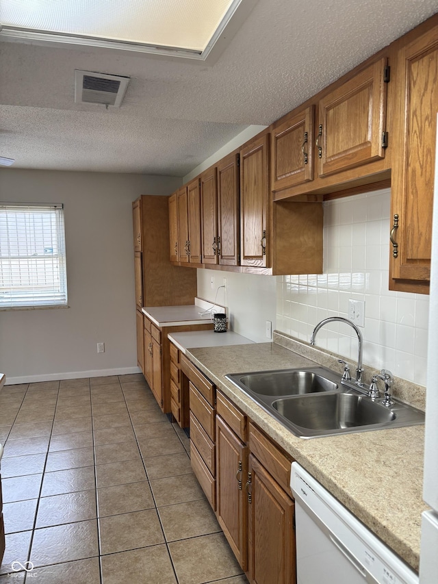 2770 Two Worlds Dr, Columbus, IN 47201 - kitchen with dishwasher, brown cabinetry, light tile patterned floors, light countertops, and a textured ceiling