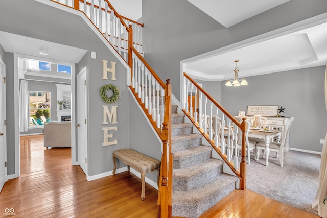 7830 Cross Crk, Avon, IN 46123 - stairs featuring a chandelier, hardwood / wood-style flooring, a high ceiling, and a fireplace