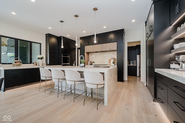1269 Chatham Rdg Ct, Westfield, IN 46074 - kitchen with dark cabinetry, a breakfast bar, backsplash, light wood-style floors, and recessed lighting