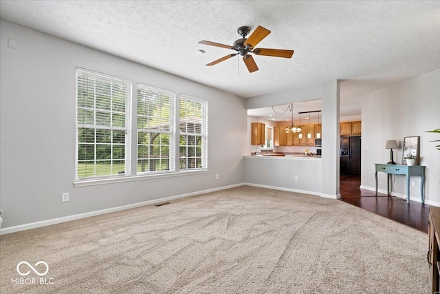 143 W Clear Lake Ct, Westfield, IN 46074 - unfurnished living room featuring carpet floors, a chandelier, a ceiling fan, and a textured ceiling