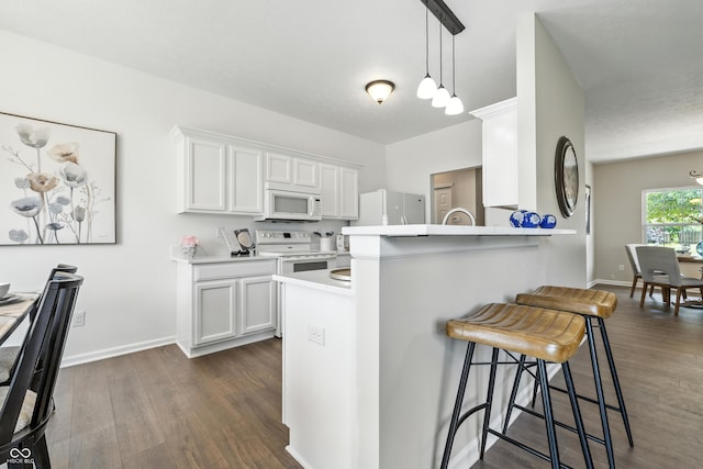 12404 Titans Dr, Fishers, IN 46037 - kitchen featuring white appliances, dark wood finished floors, a kitchen breakfast bar, light countertops, and white cabinetry