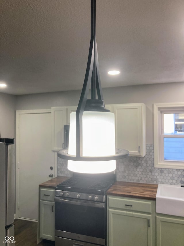 2822 Tindall St, Indianapolis, IN 46203 - kitchen with wooden counters, appliances with stainless steel finishes, decorative backsplash, a textured ceiling, and green cabinets