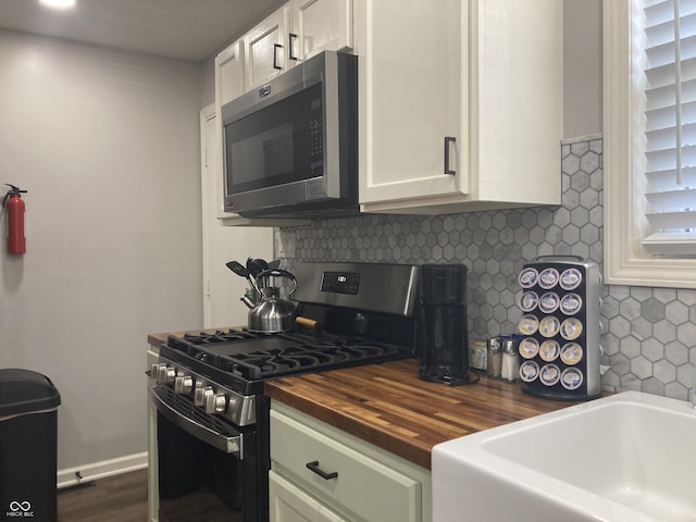 2822 Tindall St, Indianapolis, IN 46203 - kitchen featuring stainless steel appliances, wood counters, backsplash, white cabinets, and dark wood-type flooring