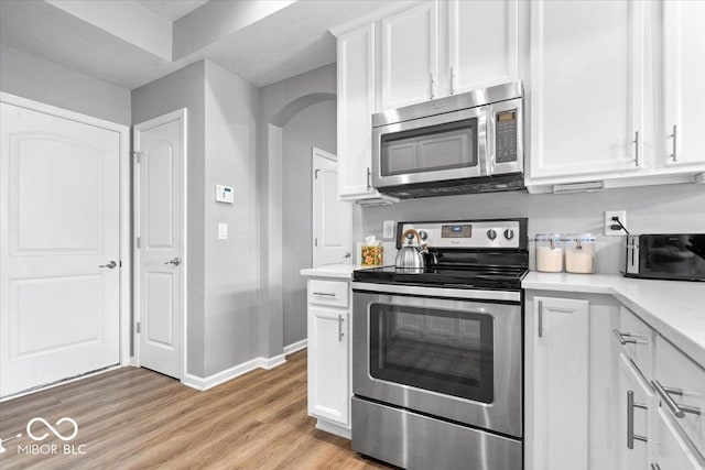 1158 Thistlewood Way, Plainfield, IN 46168 - kitchen with stainless steel appliances, arched walkways, white cabinets, light countertops, and light wood-type flooring