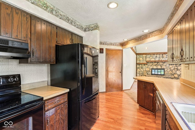 1441 N 700 W, Greenfield, IN 46140 - kitchen featuring black appliances, exhaust hood, light wood-style floors, decorative backsplash, and a textured ceiling