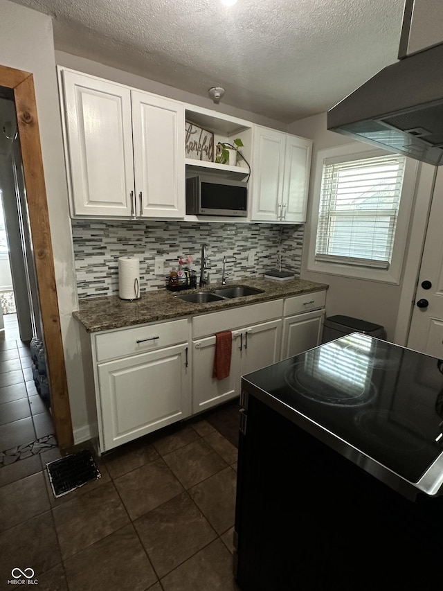 3711 Hillside Ave, Indianapolis, IN 46218 - kitchen with black electric range oven, stainless steel microwave, a textured ceiling, white cabinets, and dark tile patterned flooring