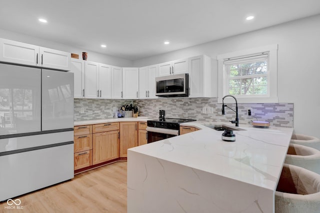301 Beech Rd, North Vernon, IN 47265 - kitchen with freestanding refrigerator, black electric range oven, light stone counters, light wood-type flooring, and a peninsula