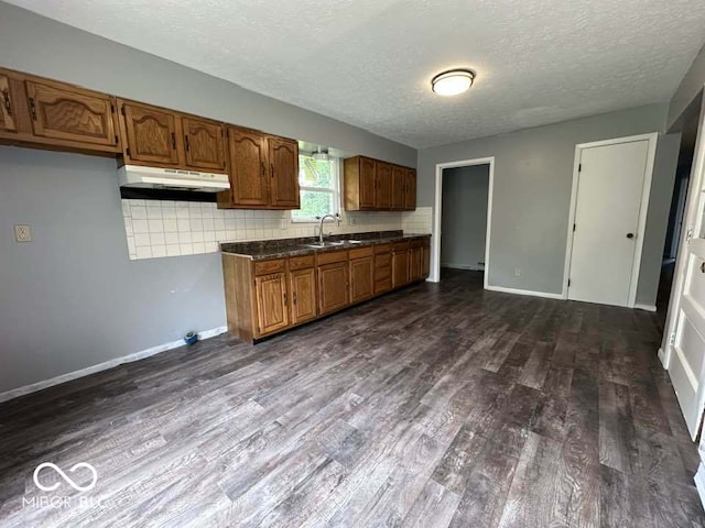 1941 W Booe Rd, Austin, IN 47102 - kitchen featuring under cabinet range hood, dark wood-type flooring, brown cabinetry, a textured ceiling, and dark countertops