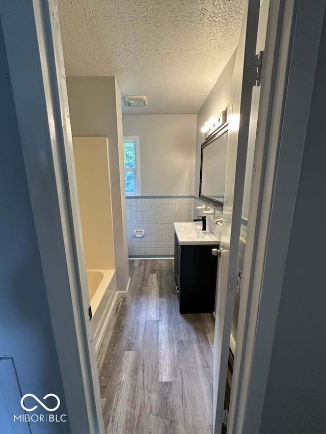 1941 W Booe Rd, Austin, IN 47102 - full bathroom with tile walls, vanity, wood finished floors, a tub to relax in, and wainscoting