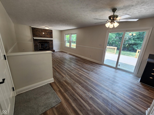 4536 Clayburn Dr, Indianapolis, IN 46268 - unfurnished living room with a textured ceiling, a ceiling fan, dark wood-style flooring, and a brick fireplace