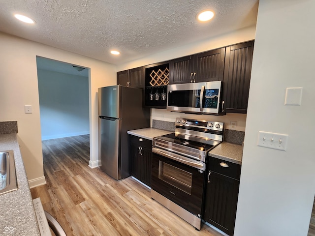4536 Clayburn Dr, Indianapolis, IN 46268 - kitchen featuring stainless steel appliances, light wood finished floors, recessed lighting, and a textured ceiling