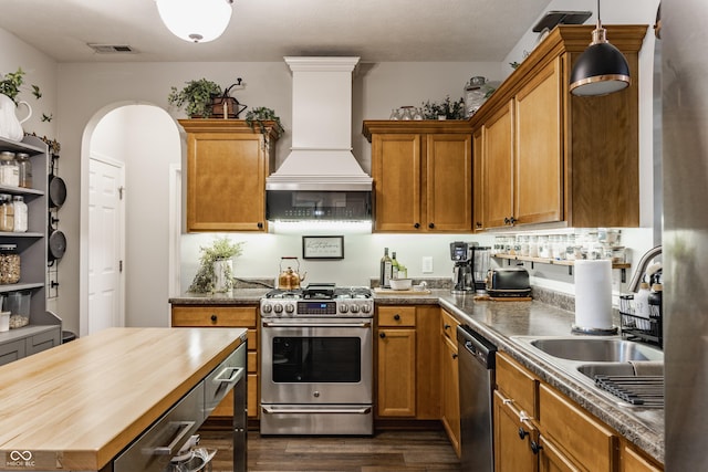 10585 Windward Dr, Indianapolis, IN 46234 - kitchen featuring appliances with stainless steel finishes, premium range hood, wood counters, dark wood-style floors, and arched walkways