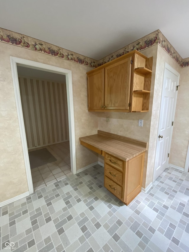 3910 S Baytree Ln, Bloomington, IN 47401 - kitchen featuring open shelves, light countertops, wallpapered walls, and built in study area