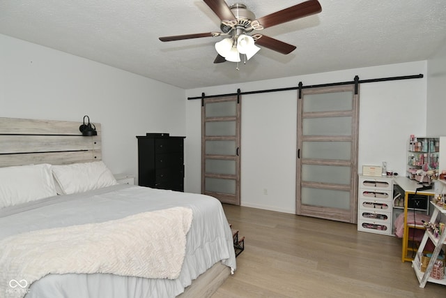 5936 Beau Jardin Dr, Indianapolis, IN 46237 - bedroom featuring a barn door, wood finished floors, a textured ceiling, and ceiling fan