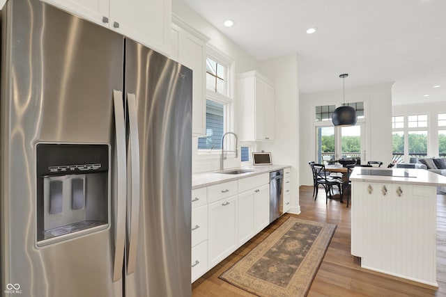 11137 Peppermill Ln, Fishers, IN 46037 - kitchen with appliances with stainless steel finishes, wood finished floors, light countertops, white cabinets, and hanging light fixtures