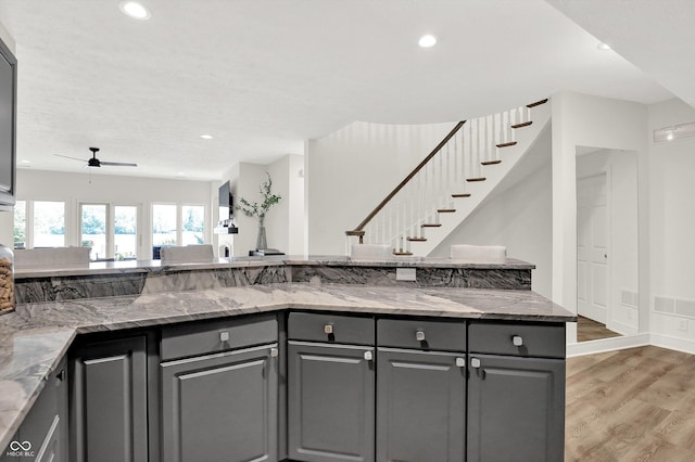 11137 Peppermill Ln, Fishers, IN 46037 - kitchen featuring gray cabinetry, light wood-style flooring, ceiling fan, light stone countertops, and open floor plan