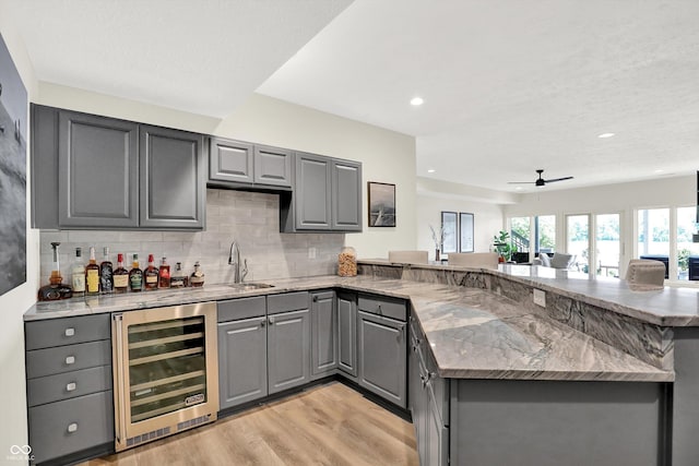 11137 Peppermill Ln, Fishers, IN 46037 - indoor bar featuring beverage cooler, light wood-type flooring, decorative backsplash, ceiling fan, and recessed lighting