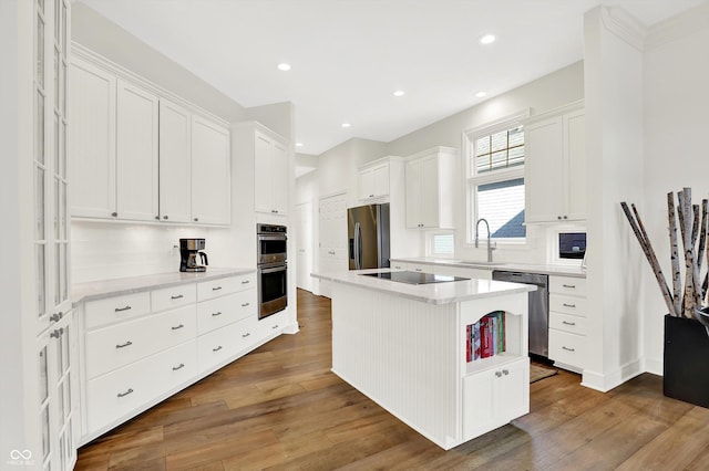 11137 Peppermill Ln, Fishers, IN 46037 - kitchen with stainless steel appliances, white cabinets, wood finished floors, a kitchen island, and recessed lighting