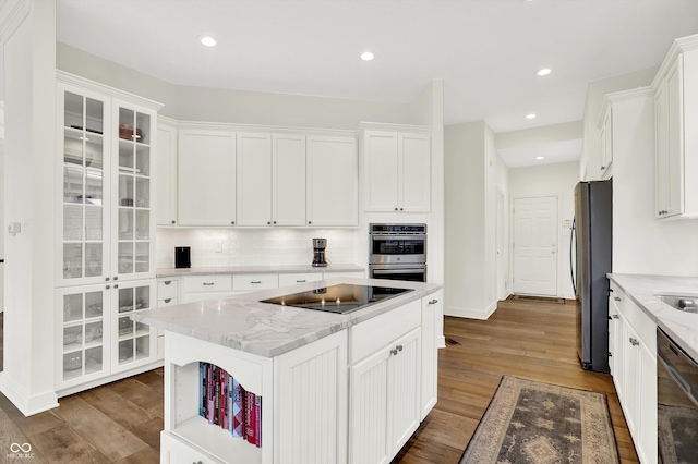 11137 Peppermill Ln, Fishers, IN 46037 - kitchen with stainless steel appliances, white cabinets, tasteful backsplash, dark wood-style flooring, and a kitchen island