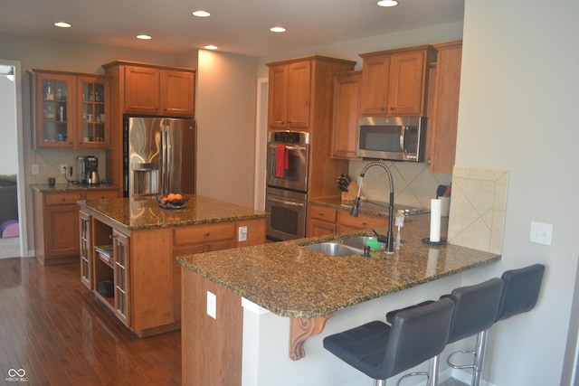 10166 Ranford Blvd, Fishers, IN 46040 - kitchen with stainless steel appliances, brown cabinets, dark stone countertops, backsplash, and glass insert cabinets