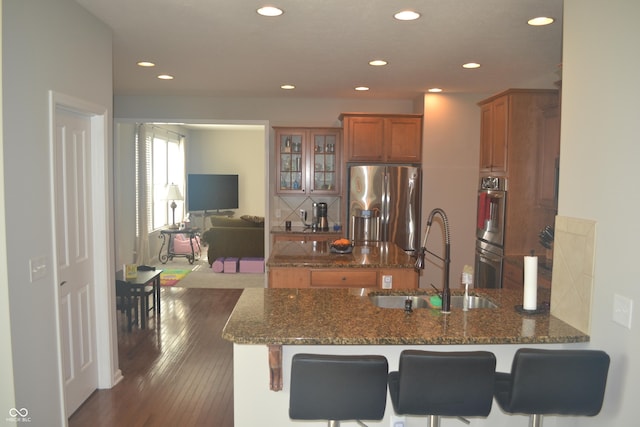 10166 Ranford Blvd, Fishers, IN 46040 - kitchen featuring stainless steel appliances, brown cabinets, a peninsula, glass insert cabinets, and recessed lighting