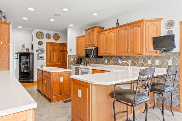 2320 Whispering Way, Indianapolis, IN 46239 - kitchen featuring stainless steel microwave, an island with sink, a peninsula, light countertops, and recessed lighting