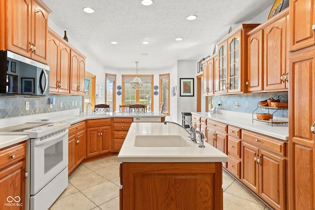 2320 Whispering Way, Indianapolis, IN 46239 - kitchen featuring electric range, stainless steel microwave, a peninsula, an island with sink, and light tile patterned floors
