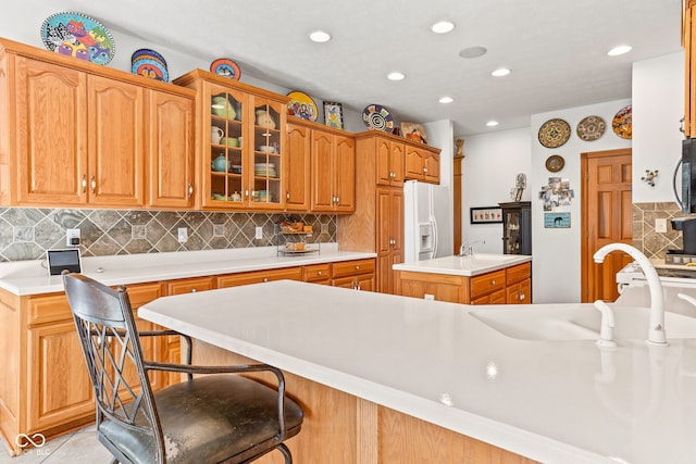 2320 Whispering Way, Indianapolis, IN 46239 - kitchen featuring white refrigerator with ice dispenser, light countertops, glass insert cabinets, decorative backsplash, and an island with sink