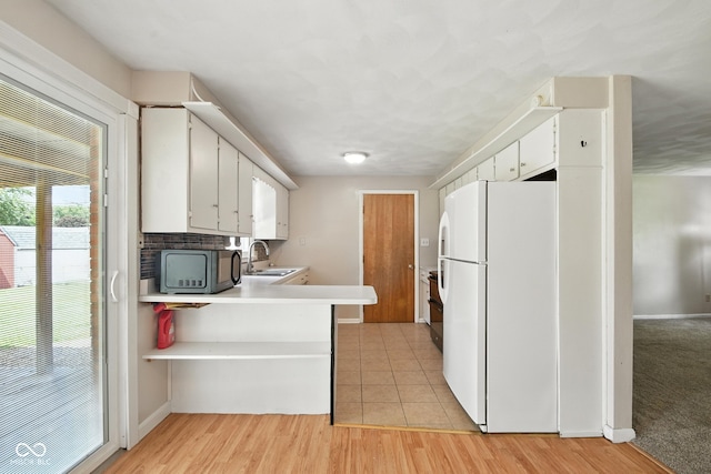 3504 White River Ct, Anderson, IN 46012 - kitchen with freestanding refrigerator, black microwave, white cabinets, light countertops, and a peninsula