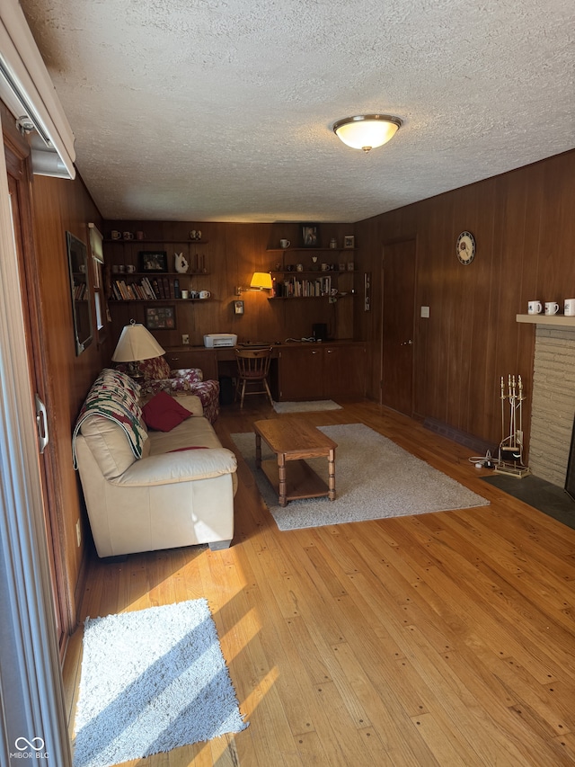 4032 Roselawn Ave, Columbus, IN 47203 - living room featuring a textured ceiling, wood walls, hardwood / wood-style flooring, and a brick fireplace