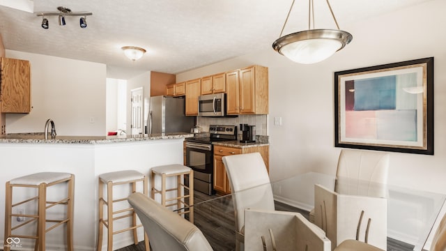 13390 Grosbeak Ct, Carmel, IN 46033 - kitchen with appliances with stainless steel finishes, a breakfast bar area, backsplash, a peninsula, and dark wood-style floors