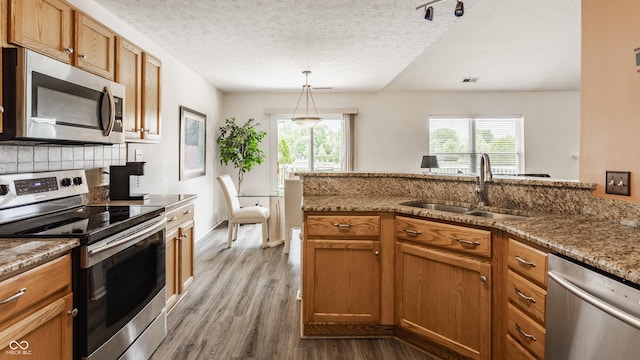 13390 Grosbeak Ct, Carmel, IN 46033 - kitchen with stainless steel appliances, brown cabinets, wood finished floors, plenty of natural light, and a textured ceiling