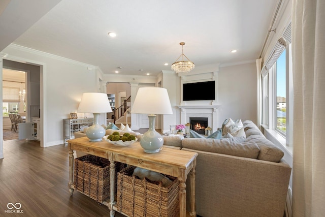 2566 Maple Creek Dr, Westfield, IN 46074 - living room featuring dark wood finished floors, a warm lit fireplace, a chandelier, ornamental molding, and ornate columns