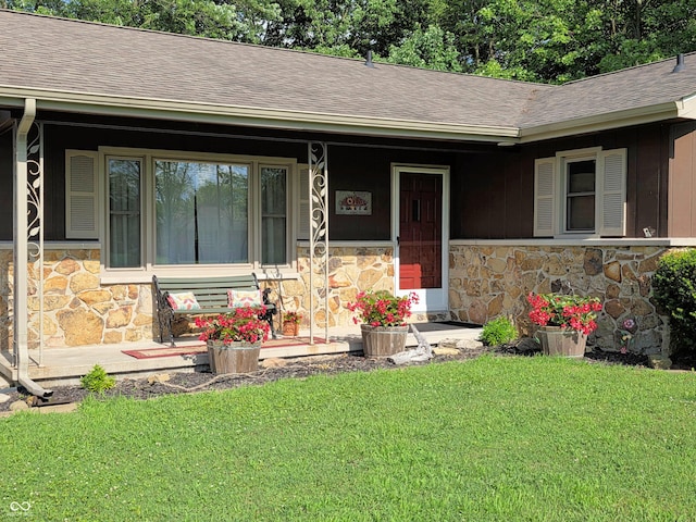 3303 N 850 E, Columbus, IN 47203 - view of exterior entry featuring stone siding, a shingled roof, a yard, and covered porch