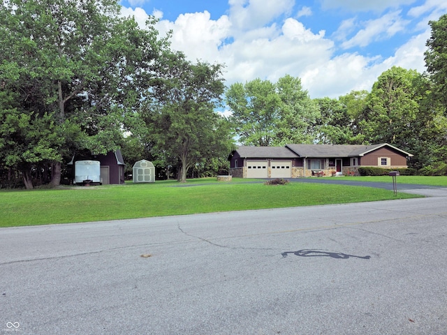 3303 N 850 E, Columbus, IN 47203 - view of front facade with a storage shed, a front lawn, an attached garage, and asphalt driveway