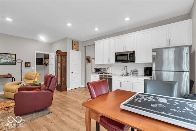 5345 Ridgecrest Ln, Mccordsville, IN 46055 - kitchen with stainless steel appliances, tasteful backsplash, light wood-style floors, white cabinetry, and light countertops