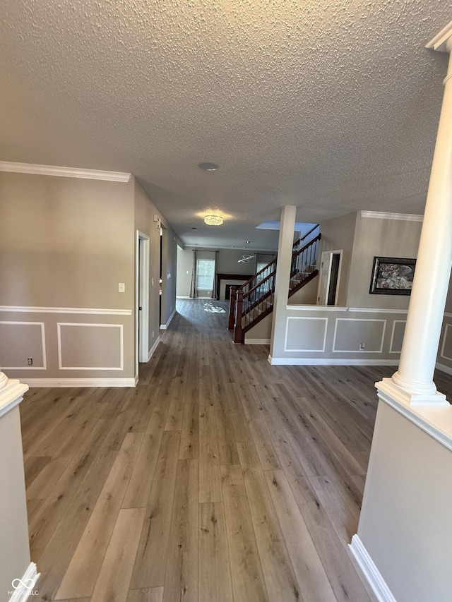 14171 Refreshing Garden Ln, Fishers, IN 46038 - hallway featuring ornate columns, stairs, a textured ceiling, a decorative wall, and ornamental molding