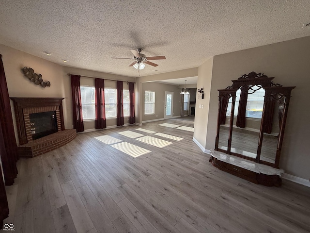 14171 Refreshing Garden Ln, Fishers, IN 46038 - unfurnished living room with a ceiling fan, a textured ceiling, wood finished floors, a fireplace, and a chandelier