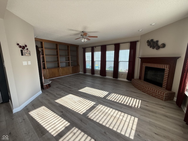 14171 Refreshing Garden Ln, Fishers, IN 46038 - unfurnished living room with a ceiling fan, a textured ceiling, wood finished floors, and a brick fireplace