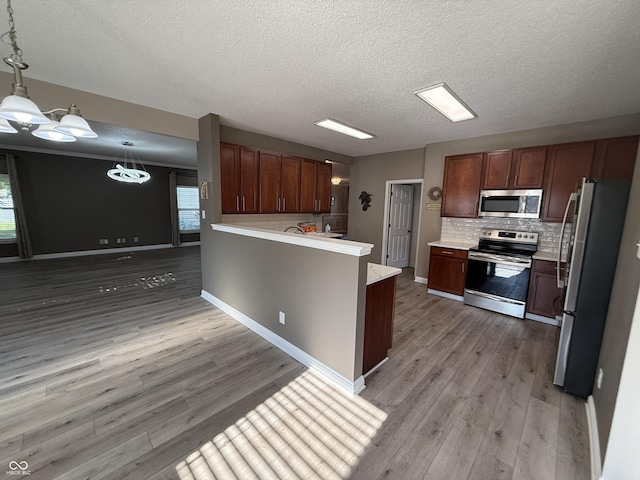 14171 Refreshing Garden Ln, Fishers, IN 46038 - kitchen featuring appliances with stainless steel finishes, light wood-style floors, backsplash, light countertops, and a textured ceiling