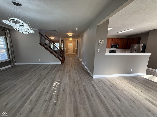 14171 Refreshing Garden Ln, Fishers, IN 46038 - unfurnished living room with a chandelier, a textured ceiling, stairs, and light wood-style floors