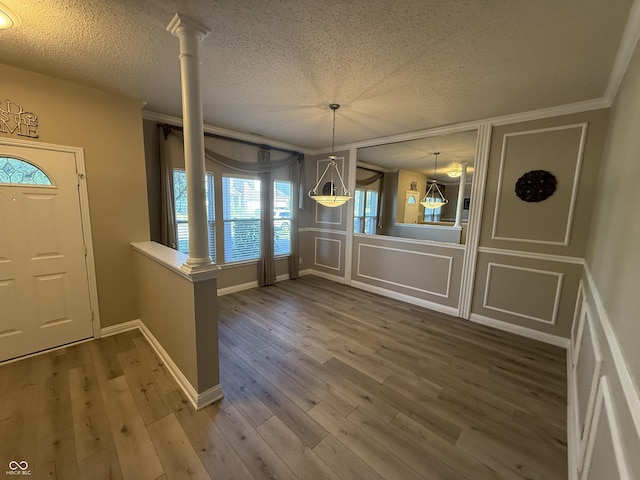14171 Refreshing Garden Ln, Fishers, IN 46038 - foyer entrance with crown molding, a textured ceiling, a decorative wall, wood finished floors, and ornate columns