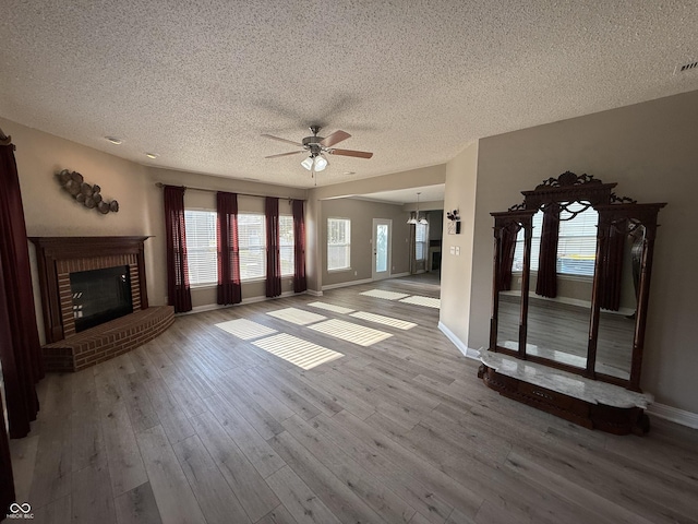 14171 Refreshing Garden Ln, Fishers, IN 46038 - unfurnished living room with a textured ceiling, a ceiling fan, wood finished floors, a fireplace, and a chandelier