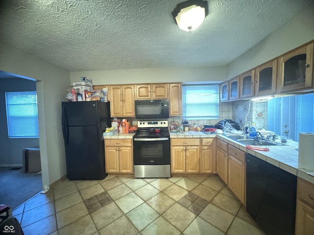4030 Hollow Creek Dr, Indianapolis, IN 46268 - kitchen with black appliances, tile countertops, glass insert cabinets, light brown cabinets, and a textured ceiling