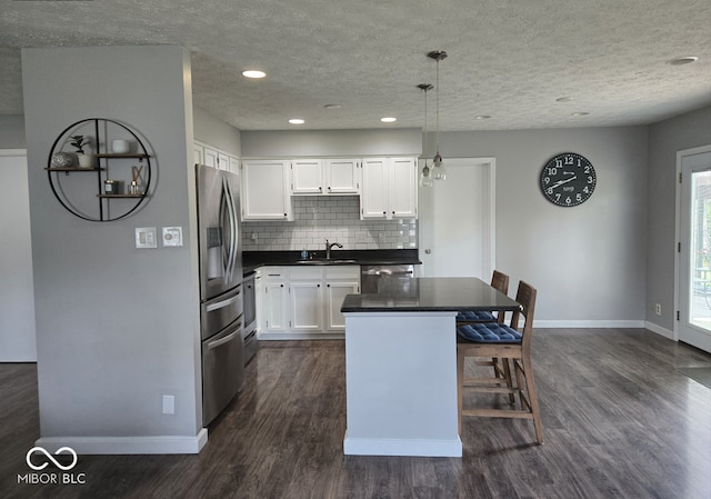 8401 Culpeper Dr, Indianapolis, IN 46227 - kitchen with dark countertops, appliances with stainless steel finishes, white cabinets, dark wood finished floors, and a kitchen island