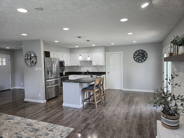8401 Culpeper Dr, Indianapolis, IN 46227 - kitchen with appliances with stainless steel finishes, dark countertops, dark wood finished floors, white cabinetry, and a center island