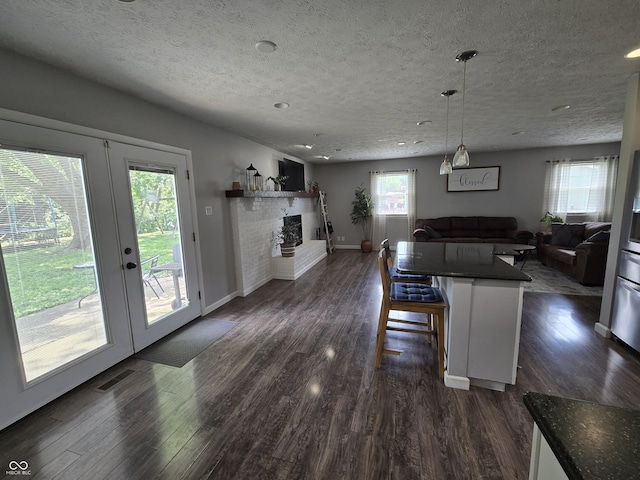 8401 Culpeper Dr, Indianapolis, IN 46227 - kitchen featuring open floor plan, dark countertops, dark wood finished floors, a brick fireplace, and a textured ceiling