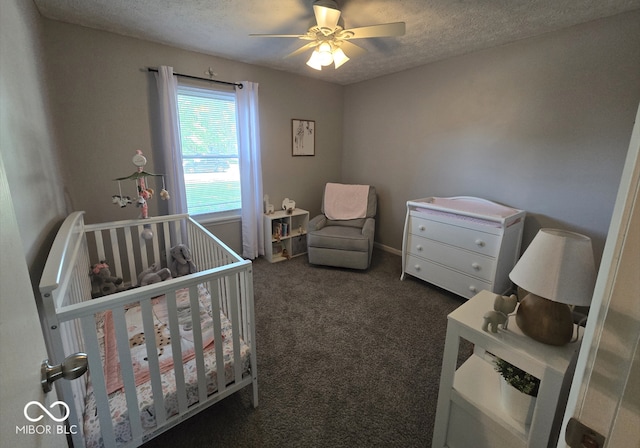 8401 Culpeper Dr, Indianapolis, IN 46227 - bedroom featuring a nursery area, dark carpet, a textured ceiling, and a ceiling fan
