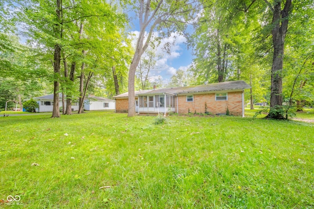 10104 Sycamore Ln, Indianapolis, IN 46239 - rear view of house with a sunroom, a yard, and brick siding